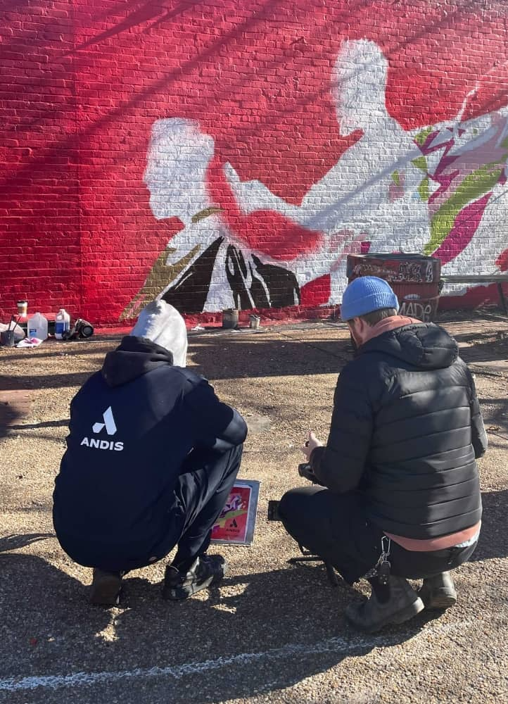 Brighter Community Atlanta two people crouched down in front of wall painting