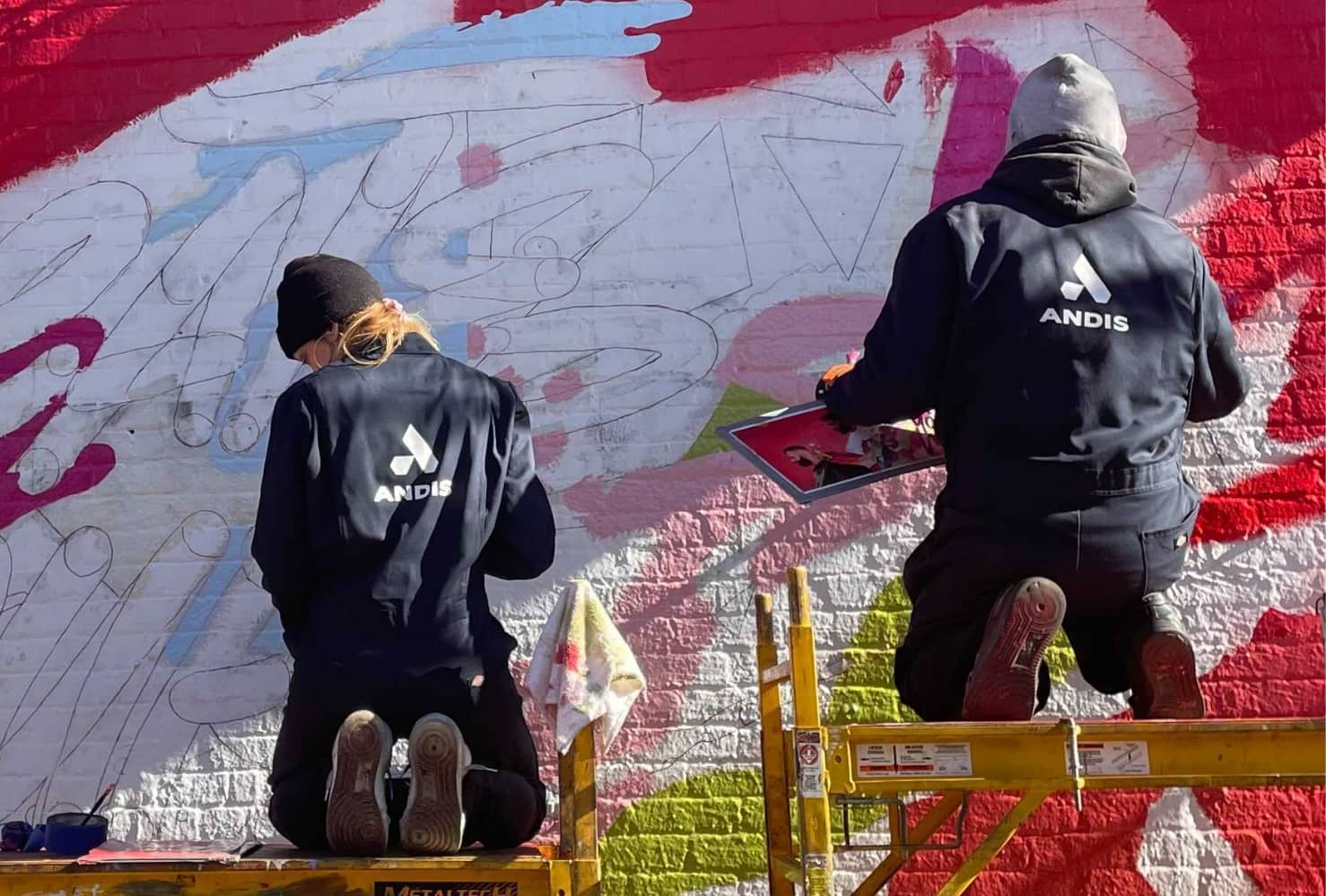 Brighter Community Atlanta 2 people on scaffolding painting a mural on the side of a building