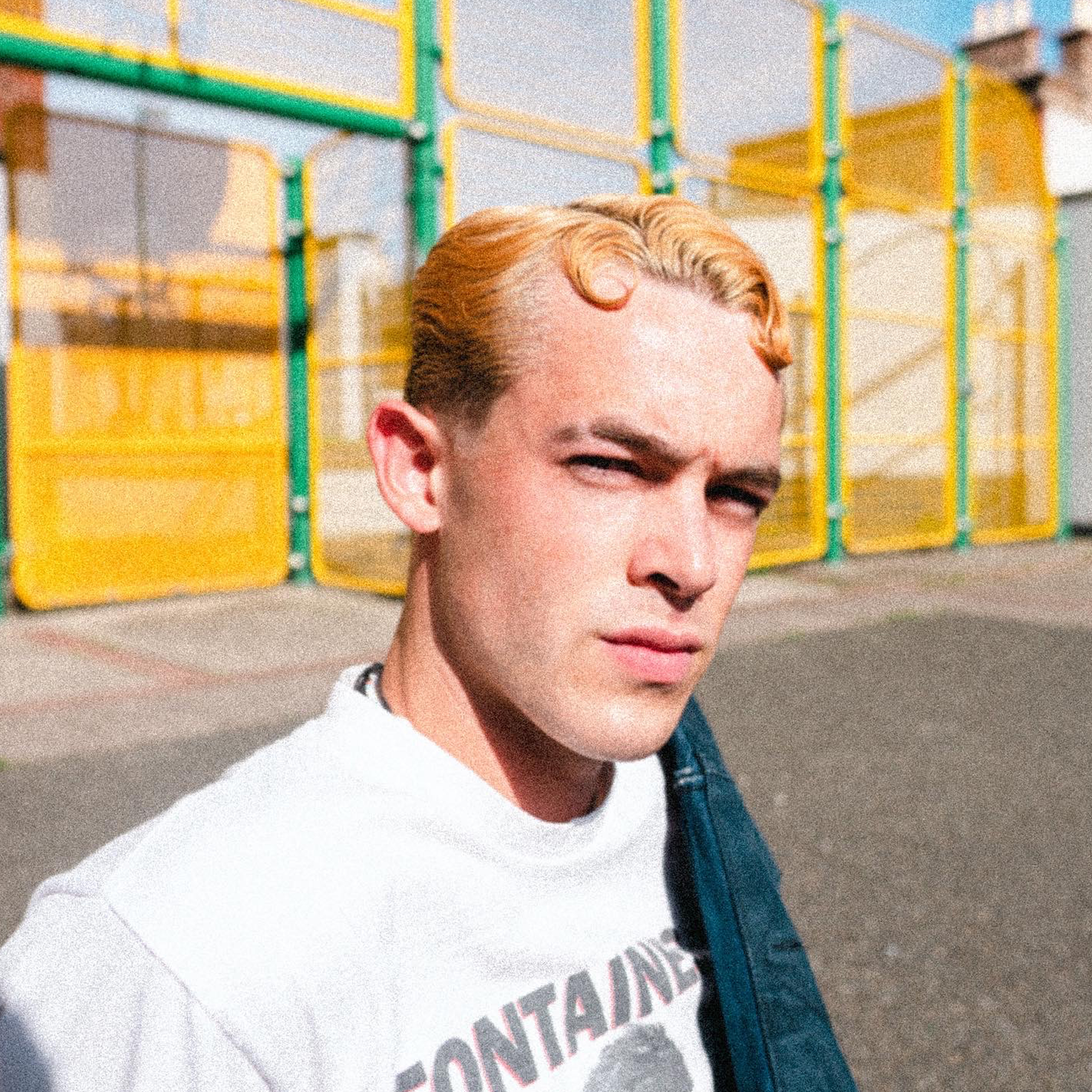 Male in white t-shirt outside in urban area with wavy top hair designed by Andis barbering tools.