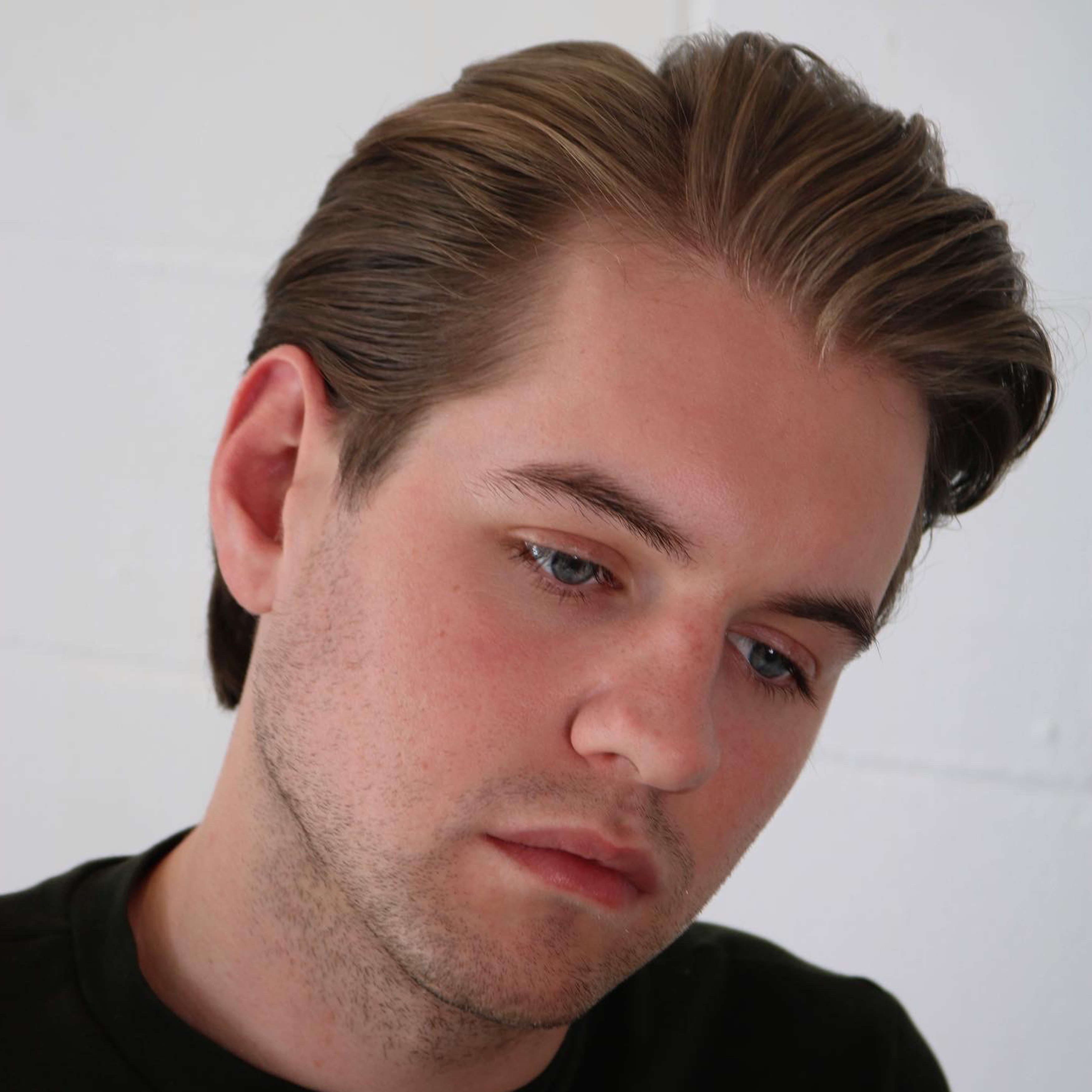 Caucasian male in black shirt with classic pompadour haircut created with barbering tools by Andis.