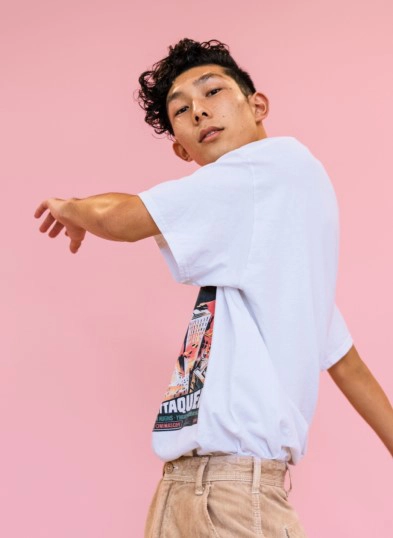 Large image of boy with black hair twirling with pink background